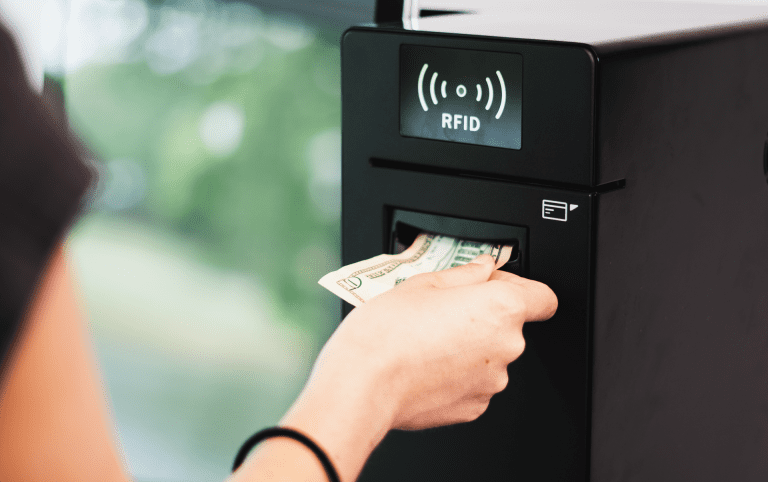 Photo of person loading the Volanté Systems CashLink Kiosk with a 10-dollar bill. The CashLink Kiosk is a point-of-sale hardware solution that allows users to load cash into their accounts.